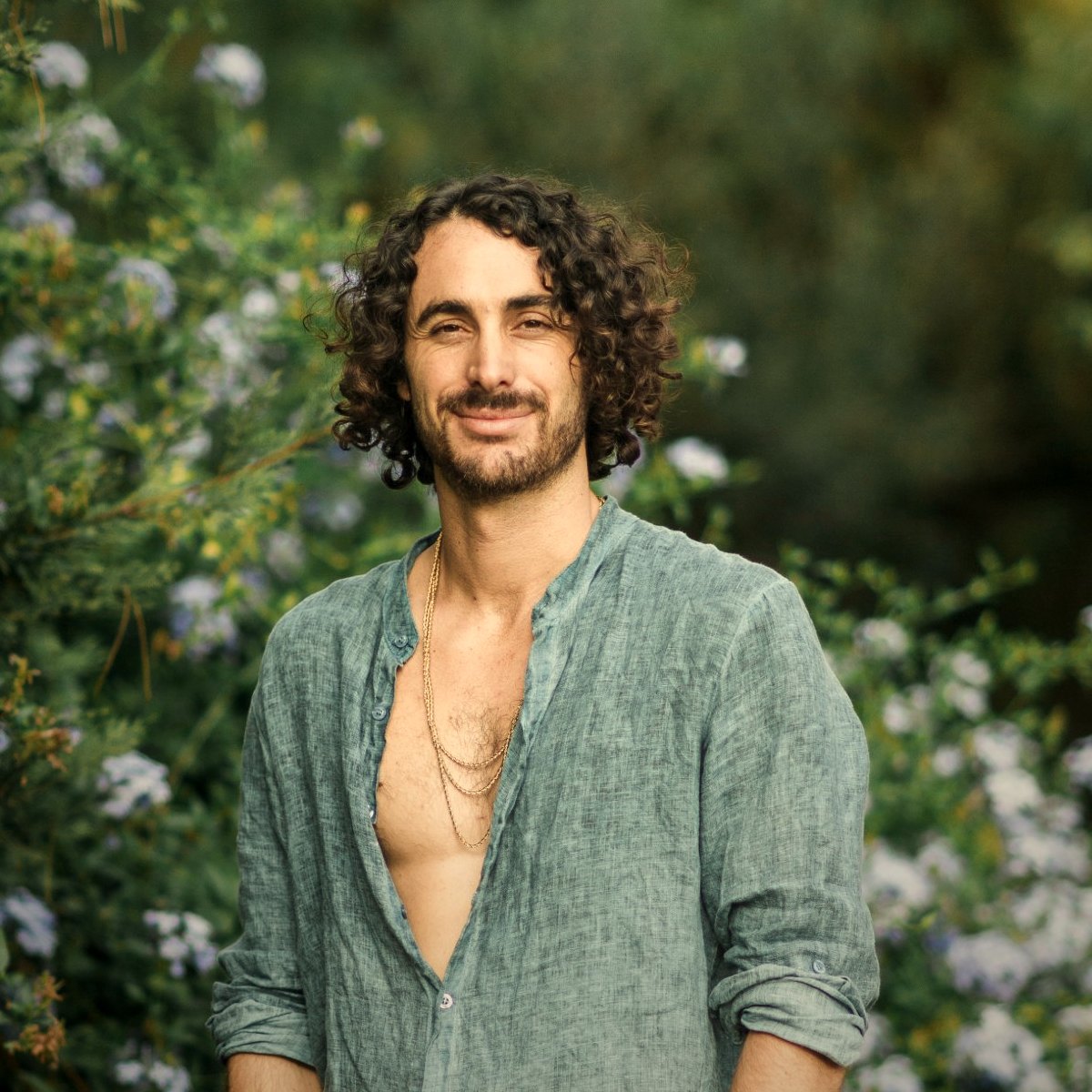 Noah standing in a garden of blue flowers, smiling at the camera